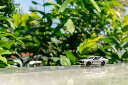 Bogor, Indonesia, March 18th, 2023 - Concept for nature and adventure with your car. Toy of old Nissan Skyline 2000 GT-R placed at the edge of glass rooftop, after some edits. photo