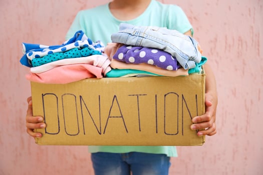 Girl holding donation box with with summer clothes. photo