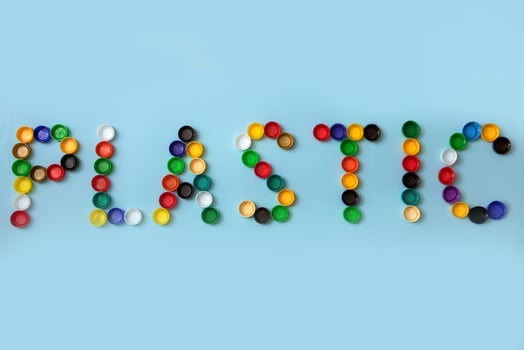 word plastic is lined with used plastic caps on a blue background photo