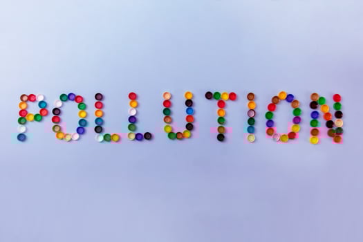 word pollution is lined with plastic bottle caps on a light purple background photo