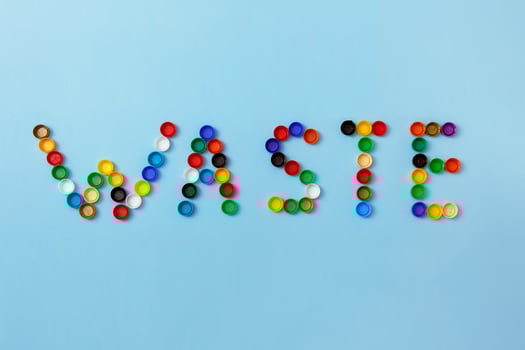 word waste is lined with plastic bottle caps on a blue background photo