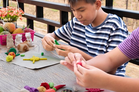 An autistic boy molding different shapes of colored plasticine prepared by parents at home in order to develop various aspects in their son which has slower brain development than normal children. photo