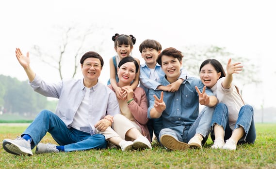 image of an asian family sitting together on the grass at the park photo