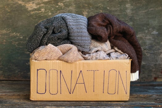 Donation box with warm things on old wooden background. photo