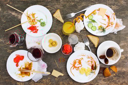 Messy table after party. Leftover food, spilled drinks, dirty dishes. photo