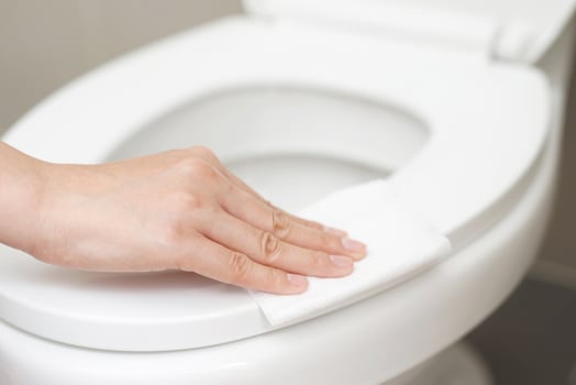 woman using tissue paper clean the toilet in the bathroom at home. photo