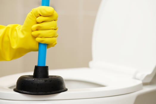 Serviceman repairing toilet with hand plunger. Clogged toilet. photo