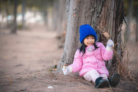 Portrait of cute asian little girl wear Winter clothes at the forest of the park,Thailand people pose for take a picture,Happy time photo