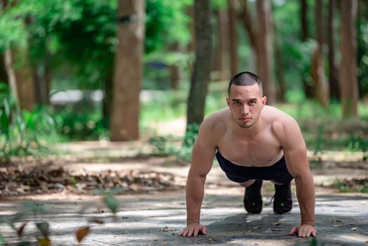 Handsome man exercises by hanging on a bar outdoor, Asian man trains for sporting events photo