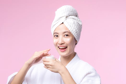 Young asian woman applying facial skincare face cream, cosmetic moisturiser on healthy natural skin make up face. Portrait glowing smile girl person model with care beauty product, spa, cosmetology. photo