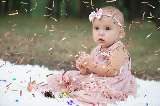 A funny little girl in a bright confetti. Child celebrates one year. Beautiful baby. photo