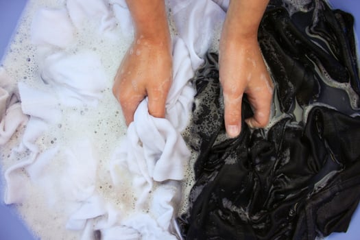 Female hand wash black and white clothes in same basin. photo