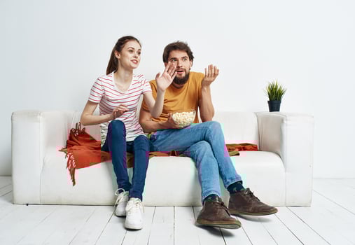Pretty woman and bearded man watching TV on the sofa indoors photo