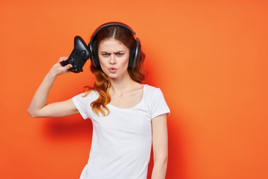 woman in white t-shirt wearing headphones joystick playing orange background photo