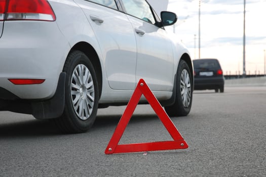 Road accident or vehicle breakdown - two cars white and black stopped on highway after collision. Red warning triangle in front of them, low angle shot photo