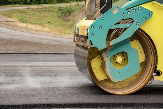 New asphalt road. the road roller working on the new road with smoke. Close photo