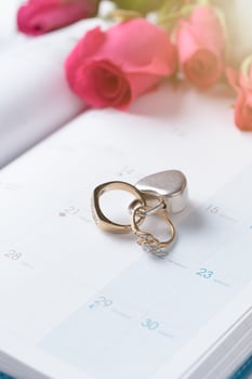 Wedding gold rings locked with lock on calender photo