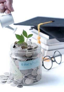 Businessman watering a tree growing out of silver coins on watering pod isolated photo