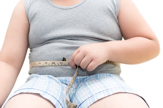 Obese fat boy measuring his belly with measurement tape photo