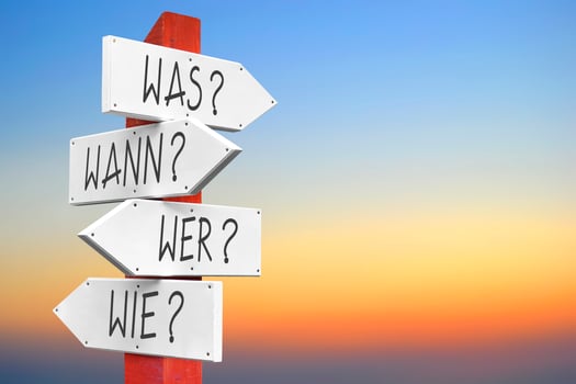 What, When, Who, How - Wooden Signpost with Four Arrows in German photo