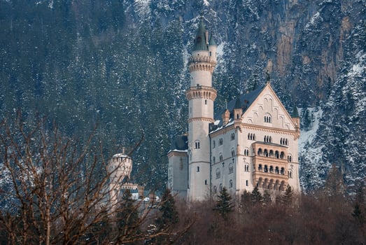 Beautiful view of the Neuschwanstein Castle or Schloss Neuschwanstein  on a winter day, with the mountains and trees capped with snow all around it. photo