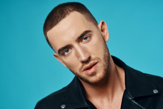 handsome man short haired leather jacket close-up blue background photo