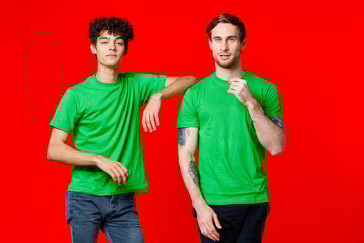 Two cheerful friends in green t-shirts joy of communication red background photo