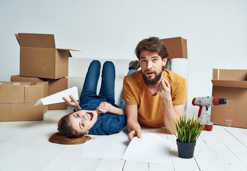 To women men on a wooden floor with boxes and a flower in a pot photo