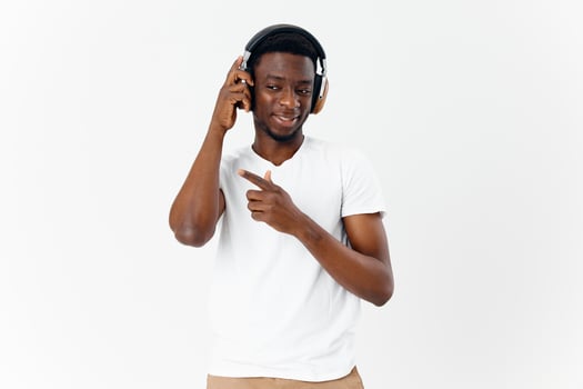 Cheerful man of African appearance listens to music with headphones emotions light background photo