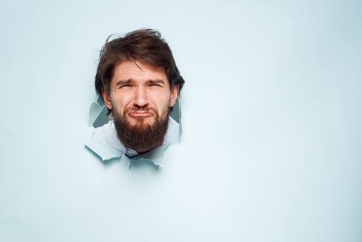 A disgruntled man looks out from behind the wall of the office manager's job photo