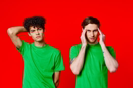 two men holding their heads in green T-shirts on a red background photo