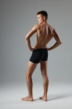 sporty man with pumped up body black shorts back view isolated background photo