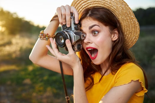 Woman photographer looks into the camera lens with open mouth surprised look nature photo