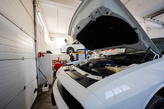 Muscle car with open hood at service repair station in lift. photo