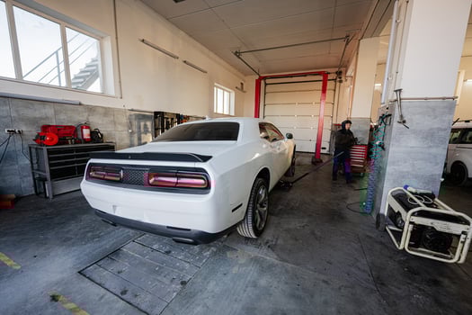 Mechanic in service repair station working with muscle car.  Man worker jacks up the car to diagnose the chassis. photo