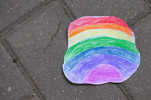 A bright rainbow made of paper colored with colored pencils lies on the asphalt. photo