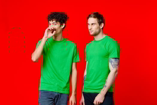 two friends in green t-shirts fun communication red background photo