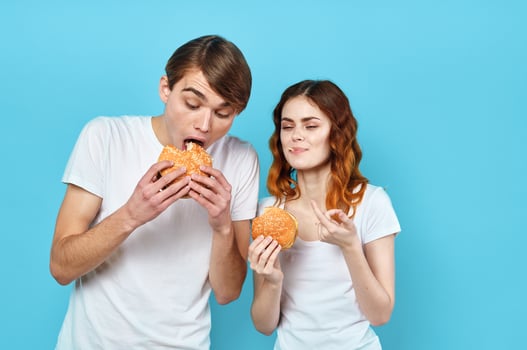 young couple in white t-shirts with hamburgers in their hands fast food snack photo