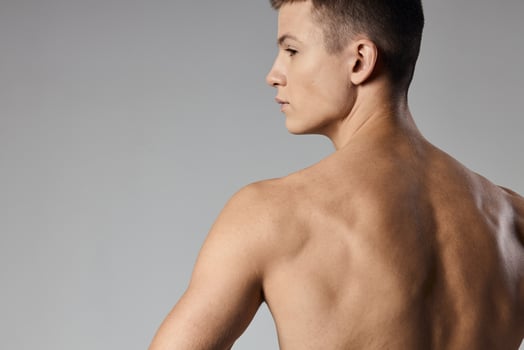 strong athlete with bulging arm muscles naked back back view gray background photo