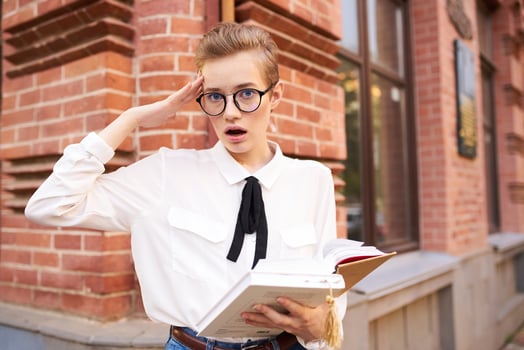 pretty woman with glasses walking around the city with a book education photo