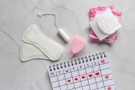Menstrual calendar with sanitary napkins, tampons, menstrual cup on white background. Concept of critical days, menstruation photo