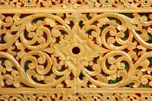Pattern of gold flower carved on stone wall background, Thai style in temple photo