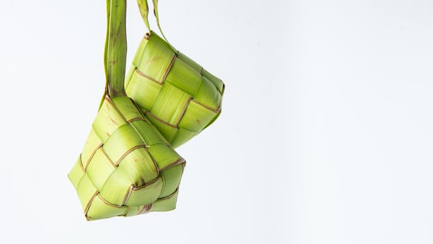 Ketupat lebaran is a typical Indonesian food during the festive season of Ketupat, Eid al Fitr, Eid al Adha, natural rice wrap made from young coconut leaves on a white background, empty space photo