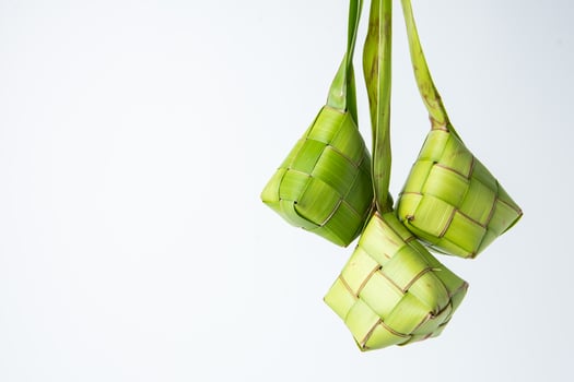 Ketupat lebaran is a typical Indonesian food during the festive season of Ketupat, Eid al Fitr, Eid al Adha, natural rice wrap made from young coconut leaves on a white background, empty space photo