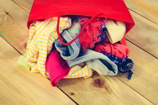 Women's clothing falls out of paper shopping bags on wooden background. photo