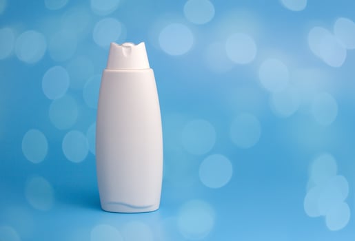 White container for cosmetics, shampoo, gel, body care product on a blue background with bokeh lights. photo