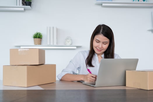 Happy young Asian woman entrepreneur, Take note after check order and Smile for sale success of online shopping store, Concept of the merchant, small business, online business, and eCommerce. photo