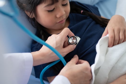 Asian woman pediatrician doctor hold stethoscope for exam a little girl patient and heck heart lungs of kid, Good family doctor visiting child at home, Healthcare and medicine for childhood concept. photo