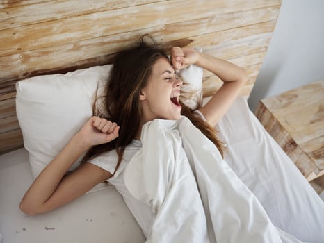 happy woman waking up in bed yawning photo