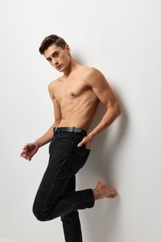 A man with a naked torso in black trousers posing portrait of self-confidence photo